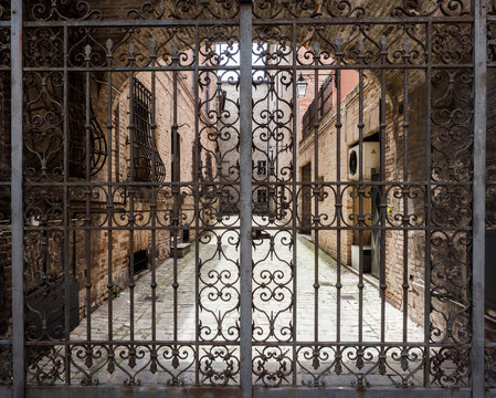 Hand-worked wrought iron gate with internal courtyard of an old Italian palace.