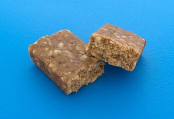 Cashew and date energy bar broken in half on a blue cutting board.