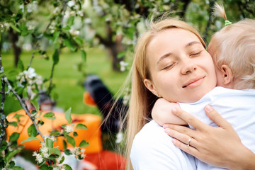 Mom is hugging her child in the summer in the park. The concept of a family and a healthy lifestyle