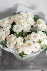 white spray roses. Bouquet of beautiful flowers on wooden table. Floristry concept. the work of the florist at a flower shop. Vertical photo