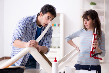 Wife helping husband to repair broken chair at home