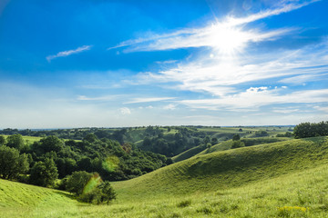 Beautiful green hills with cloudscape and strong sun