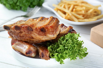 Plate with delicious grilled ribs on table
