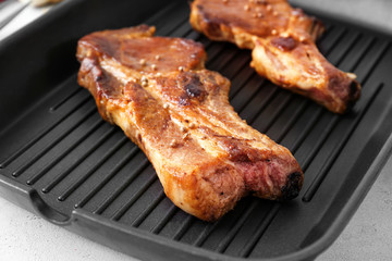 Grill pan with delicious ribs on table, closeup