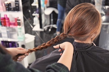 Obraz na płótnie Canvas Professional stylist cutting off woman's braid in salon