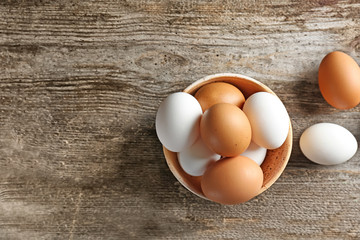 Bowl with chicken eggs on wooden table