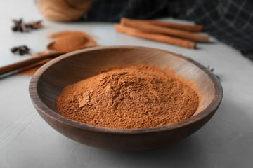 Bowl with aromatic cinnamon powder on table