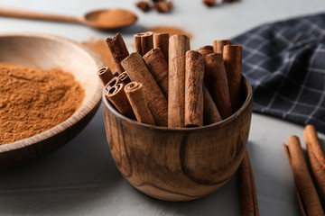 Bowl with aromatic cinnamon sticks on table