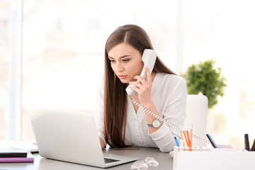 Young woman talking on phone at workplace