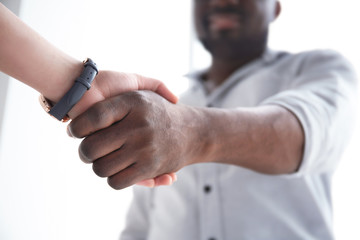 Man and woman shaking hands on light background, closeup. Unity concept