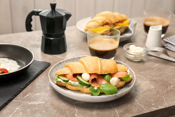 Plate with tasty croissant sandwich on table
