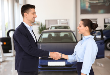 Young salesman working with client in car dealership