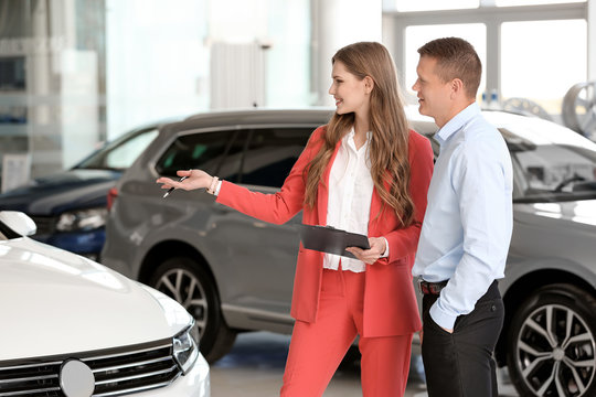Young saleswoman working with client in car dealership