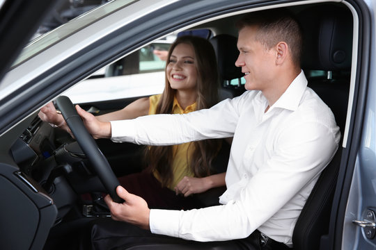 Saleswoman consulting client in auto at car dealership
