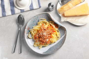 Plate with delicious pasta bolognese on light background, top view