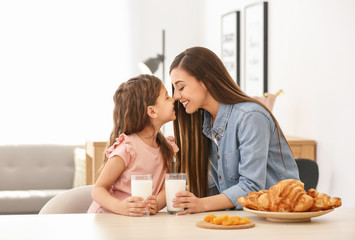 Mother and daughter having breakfast with milk at table
