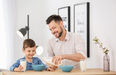Father and son having breakfast with milk at table