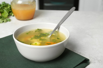 Bowl with delicious hot broth on table. Cold treatment