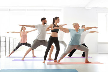Fototapeta na wymiar Group of people in sportswear practicing yoga indoors