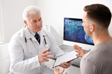 Fototapeta premium Male doctor working with patient in clinic. Cardiology consultation