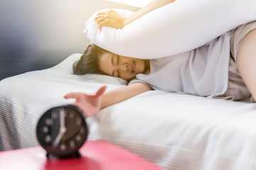 Female stretching her hand to ringing alarm to turn off alarm clock,Woman hates getting stressed waking up early