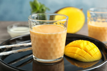 Glass with healthy detox smoothie and mango on tray