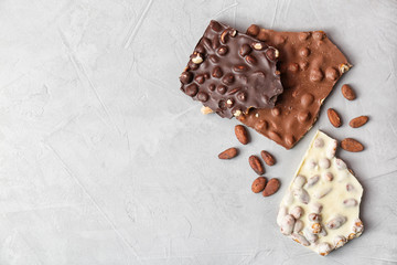 Different chocolate bars with nuts on grey background, top view