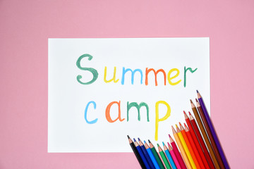 Pencils and words SUMMER CAMP on color background, top view