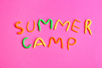 Words SUMMER CAMP made from modelling clay on color background, top view