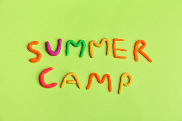 Words SUMMER CAMP made from modelling clay on color background, top view