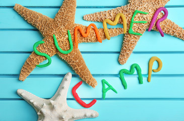 Flat lay composition with words SUMMER CAMP made from modelling clay and sea stars on color background