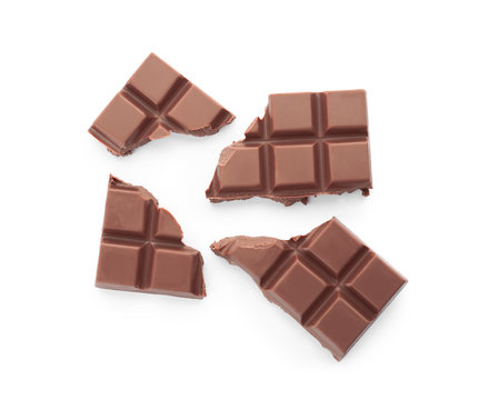 Delicious milk chocolate pieces on white background, top view