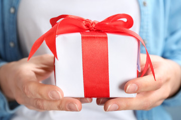 Young woman holding beautifully decorated gift box, closeup