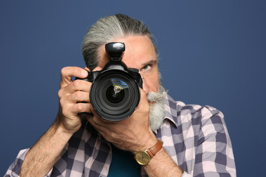 Male photographer with professional camera on color background