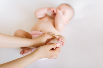 Mother hand massaging foot of her baby on white background