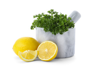 Mortar with green fresh parsley and lemons on white background