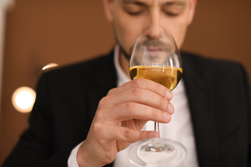 Young man with glass of wine indoors