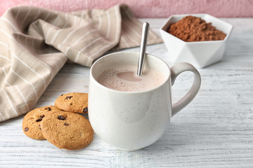 Tasty cookies and mug with hot cocoa drink on table