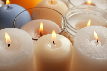 Fototapeta na wymiar Burning wax candles of different shapes and colors, closeup