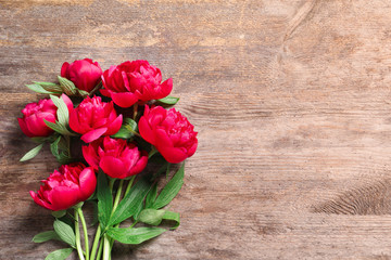Beautiful blooming peony flowers on wooden background, top view