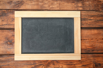 Fototapeta na wymiar Empty clean chalkboard on wooden background