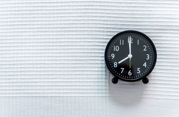 Close up of black alarm clock on the white bed,Copy space