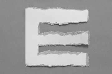 alphabet letters recycled torn paper craft on gray background (E)