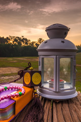 Quran, beads, and lantern on old wood with a beautiful sunrise as background. Ramadhan Concept.