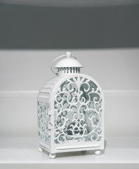 An empty white vintage candle lantern. Vintage lantern design with glass for home decoration.