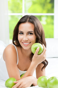 Young happy smiling woman with apples, indoors
