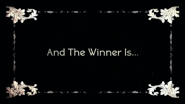 A re-created film frame from the silent movies era, showing an intertitle text: and the winner is.
