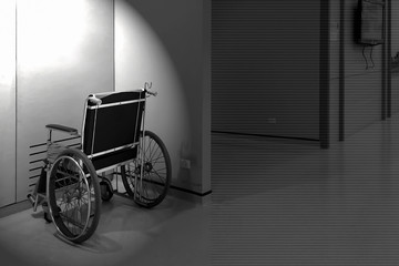 Fototapeta na wymiar Black and white photography of lonely wheelchair in the hospital empty room.