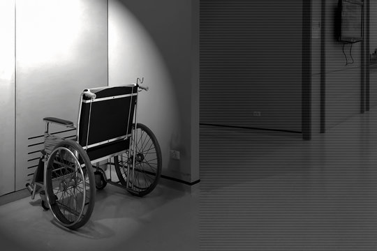 Black and white photography of lonely wheelchair in the hospital empty room.
