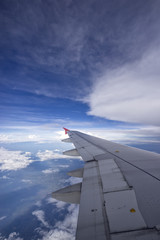 Beautiful clouds with blue sky, through airplane window, aircraft wing on a side.